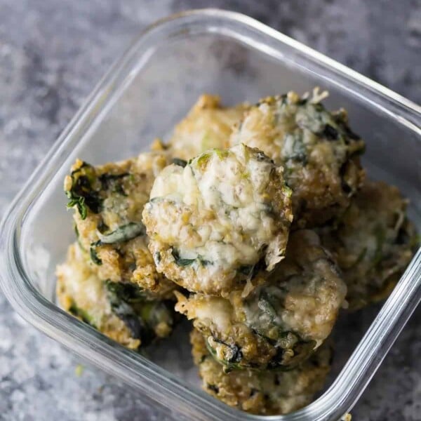 glass meal prep container with cheesy spinach quinoa cups on gray counter