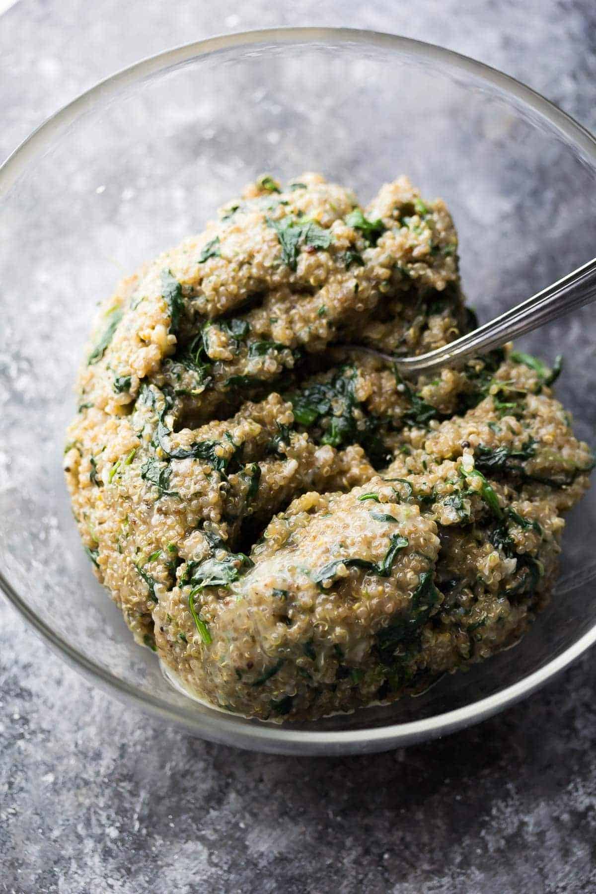 mixture for Cheesy Spinach Quinoa Cups in large glass bowl with spoon