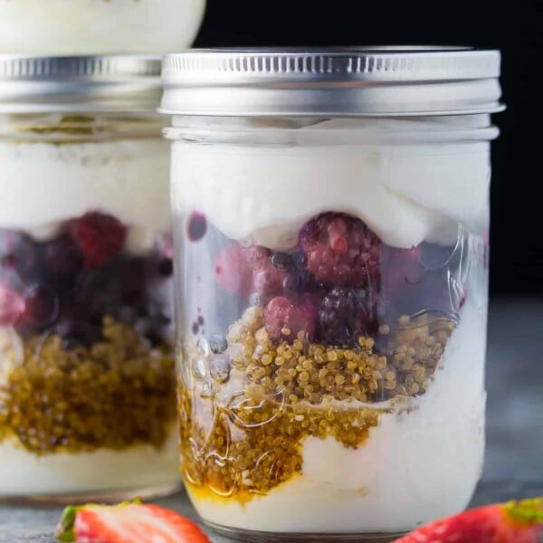 close up shot of berry breakfast parfaits in two mason jars with strawberries