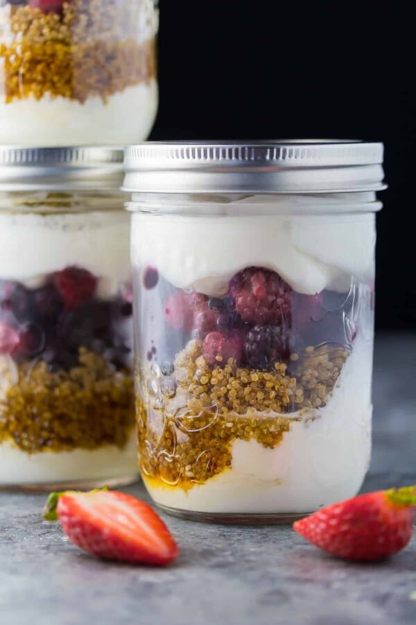 close up shot of berry breakfast parfaits in two mason jars with strawberries