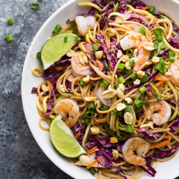 overhead shot of spiralized veggie thai noodle bowl in large white bowl with fresh limes