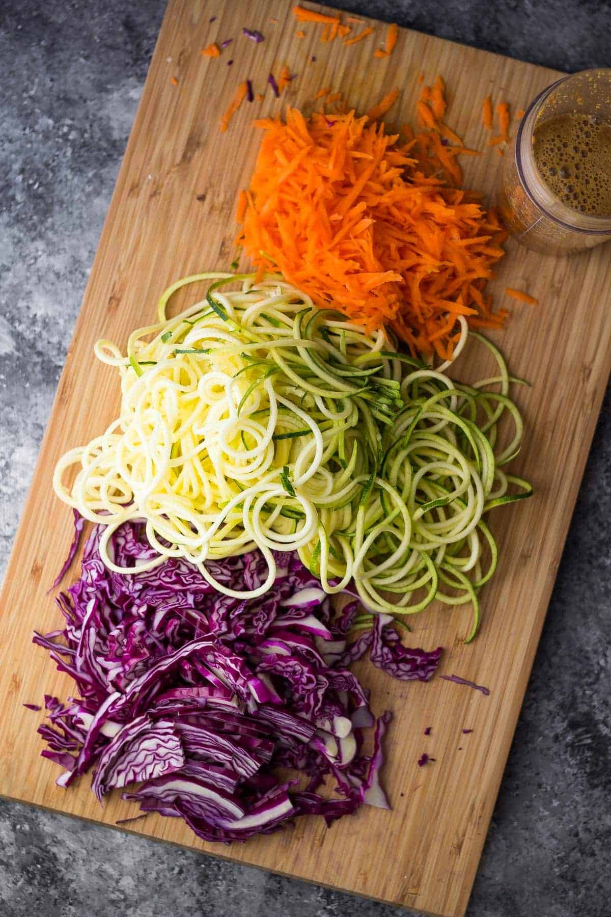 overhead view of shredded and spiralized vegetables for noodle bowls on wood cutting board