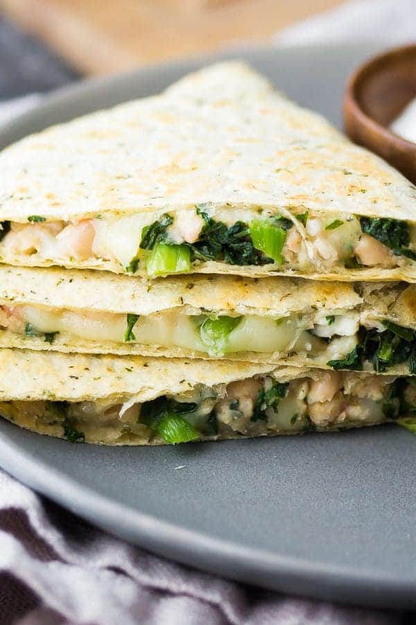 white bean kale quesadillas on gray plate with sour cream