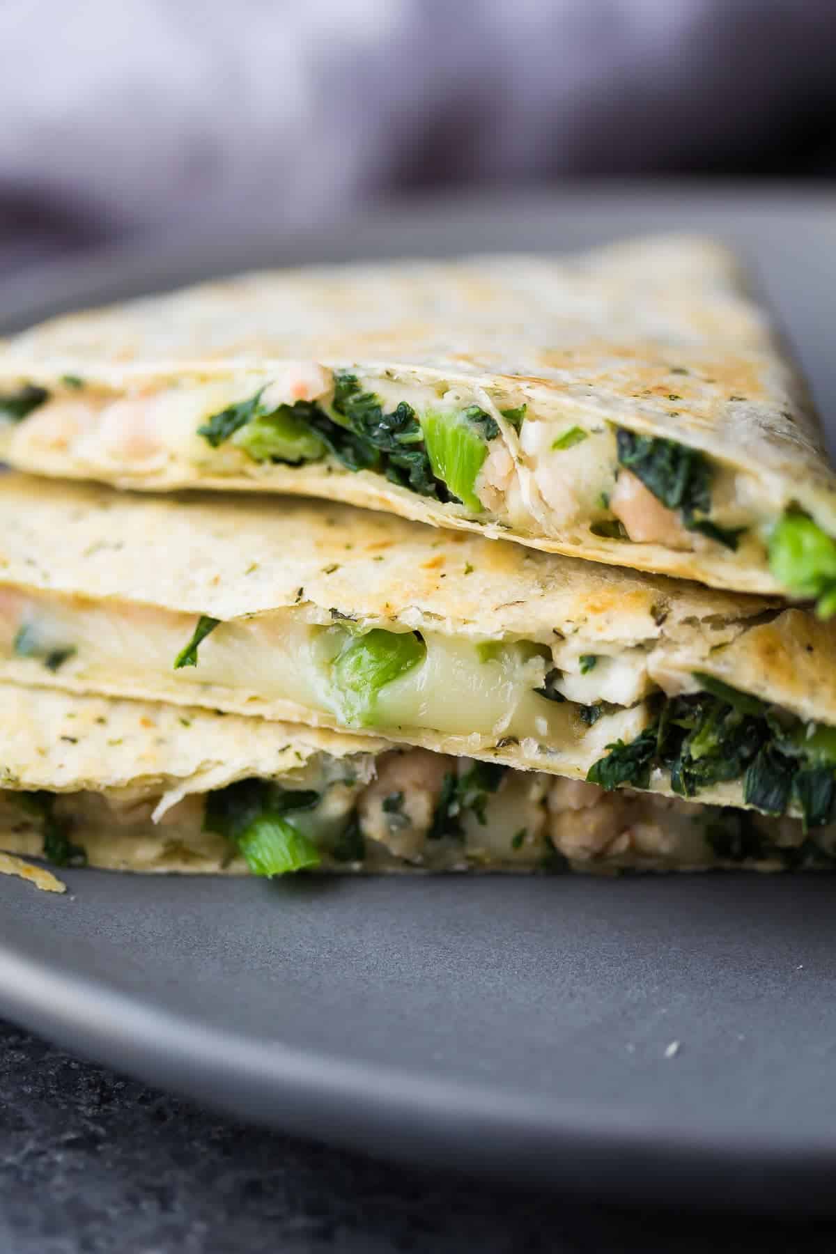 Stack of three Smashed White Bean and Spinach Quesadillas on gray plate