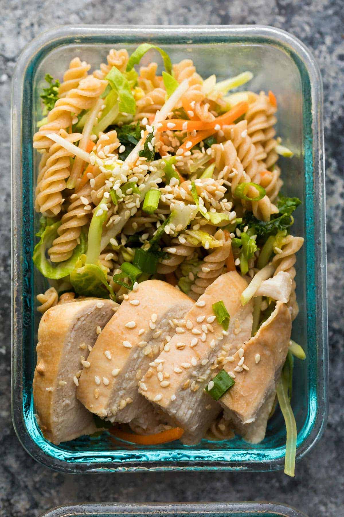 overhead shot of Sesame Chicken Pasta Salad in glass meal prep container