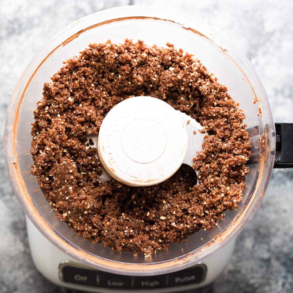 overhead view of ingredients for Chocolate Almond Quinoa bars in the food processor after pulsing