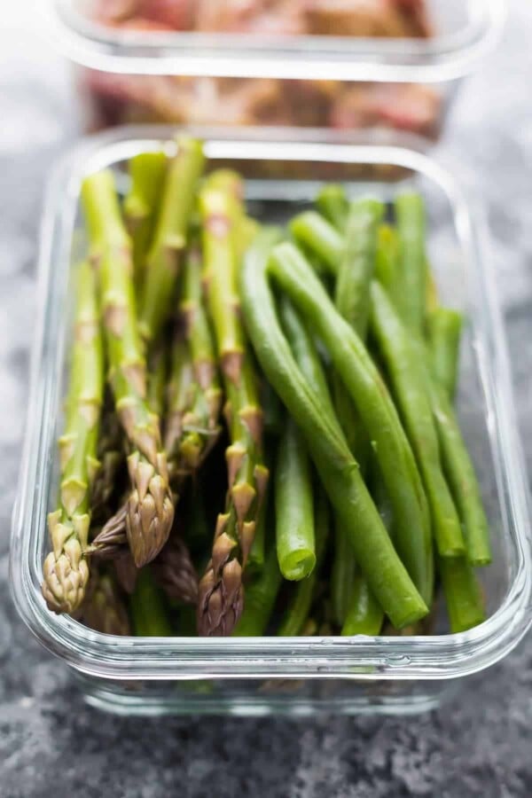 Close up view of cut green beans and asparagus in glass container