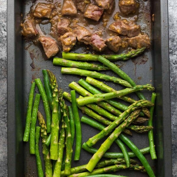 overhead shot of hoisin ginger steak asparagus and green beans on sheet pan