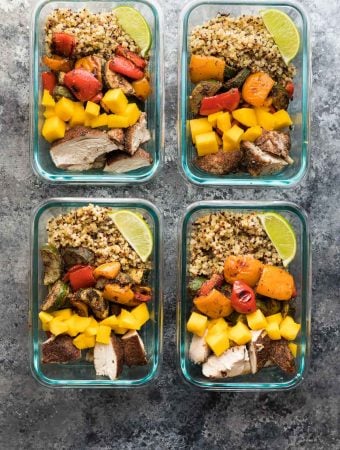 four glass meal prep containers with jamaican chicken quinoa lunch bowls