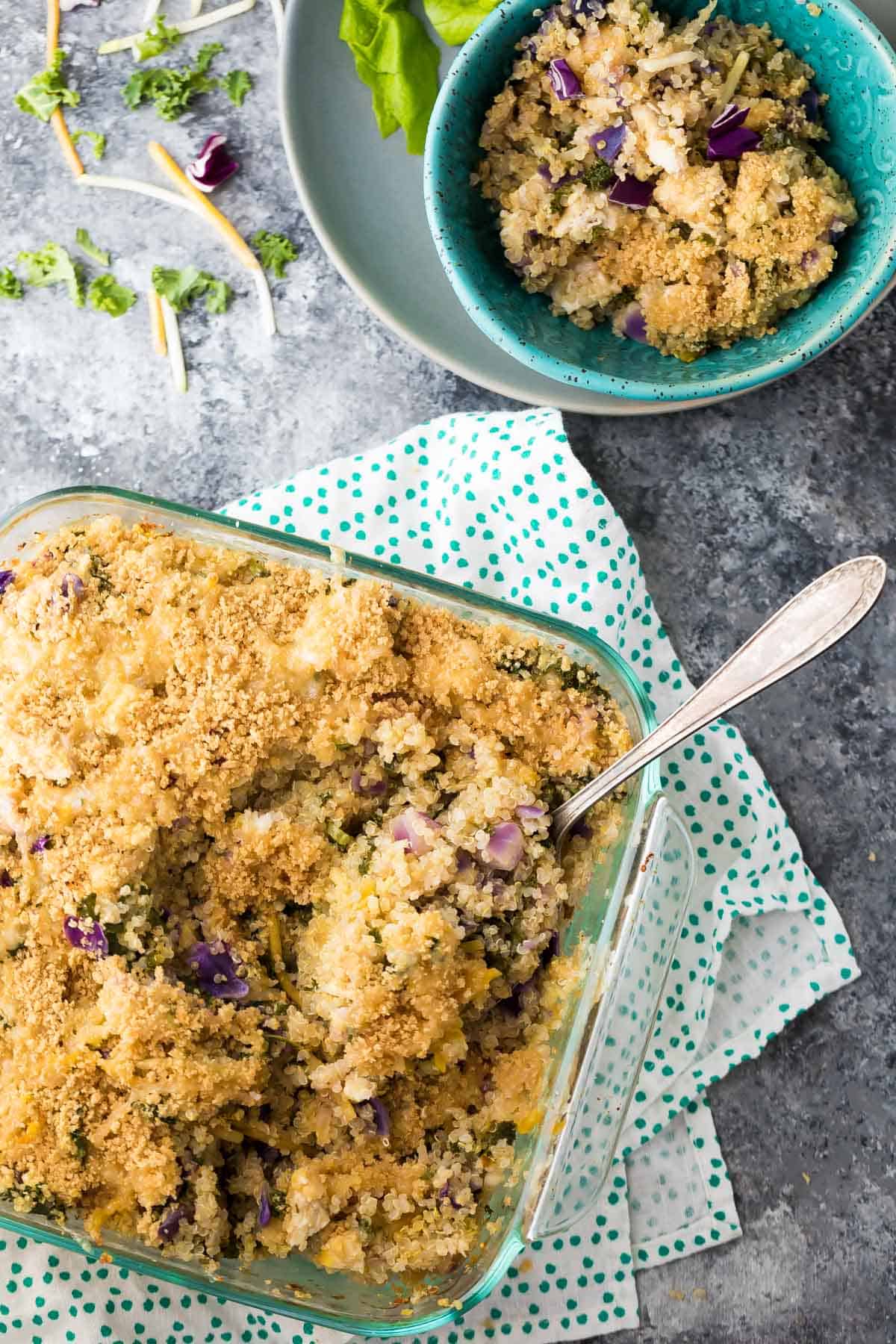 overhead view of Mediterranean Chicken Quinoa Casserole in glass casserole dish with a serving in a blue bowl