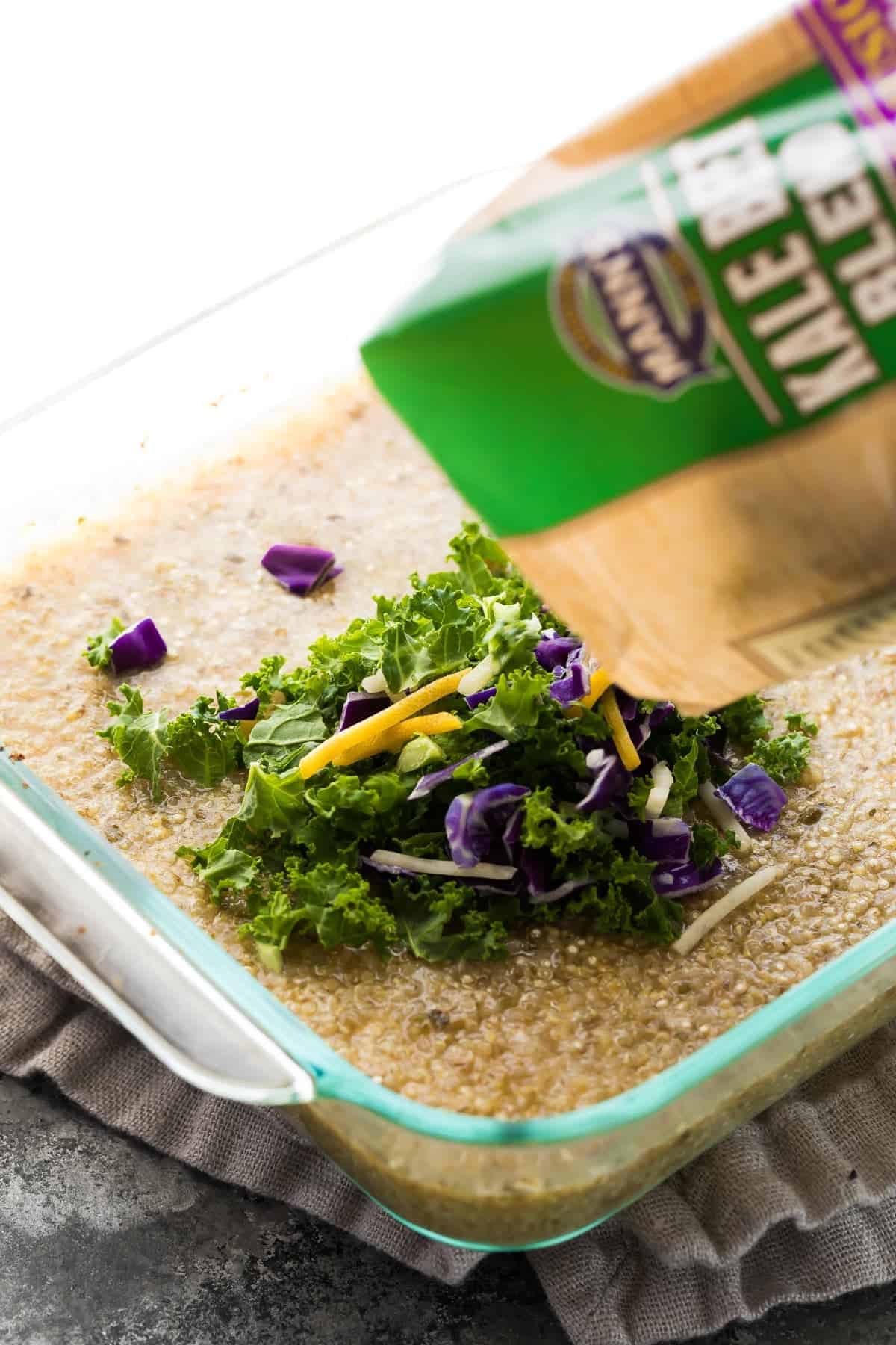 Kale beet blend salad mix being poured into the glass casserole dish