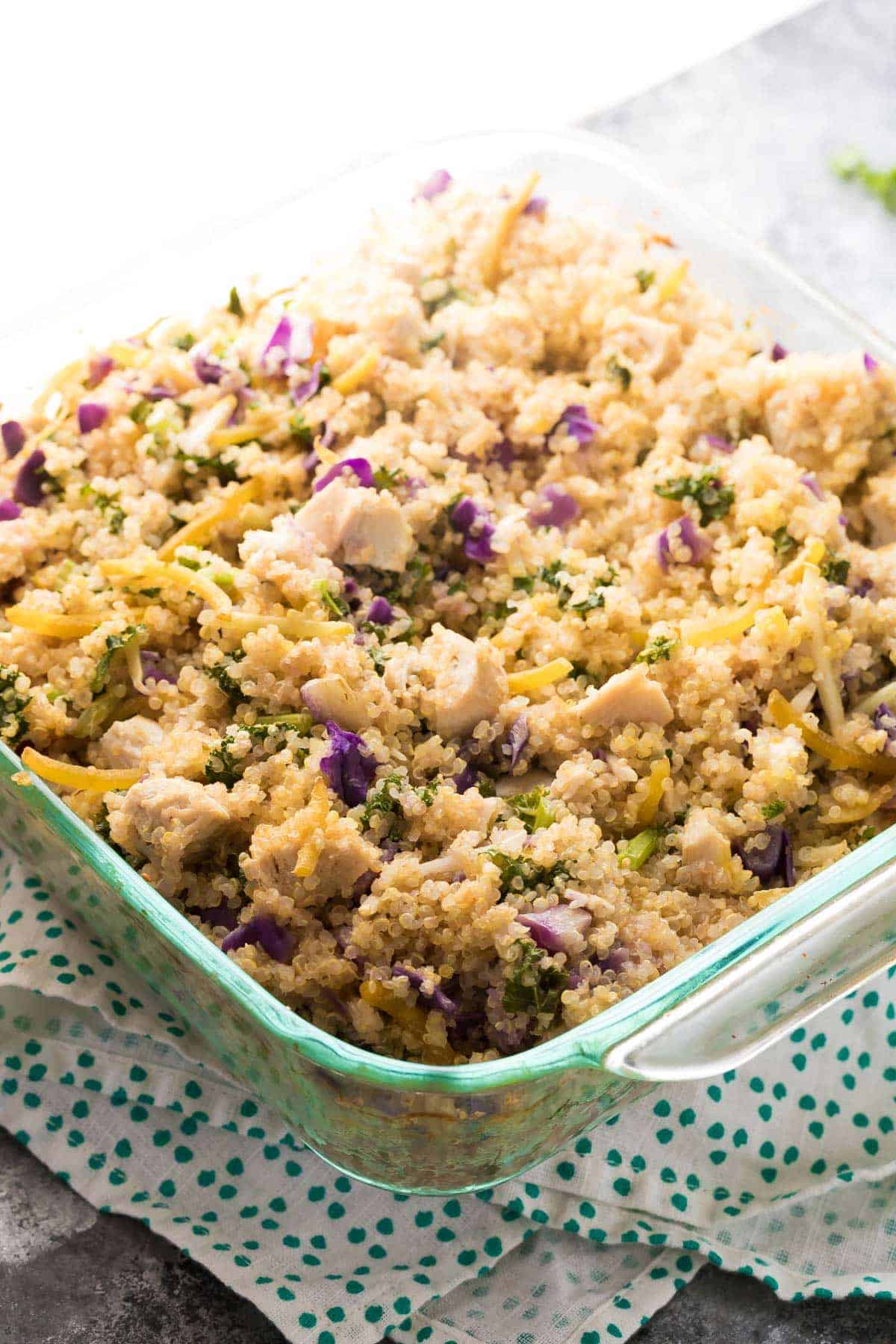 Mediterranean Chicken Quinoa Casserole prepped in glass baking dish on blue and white tea towel