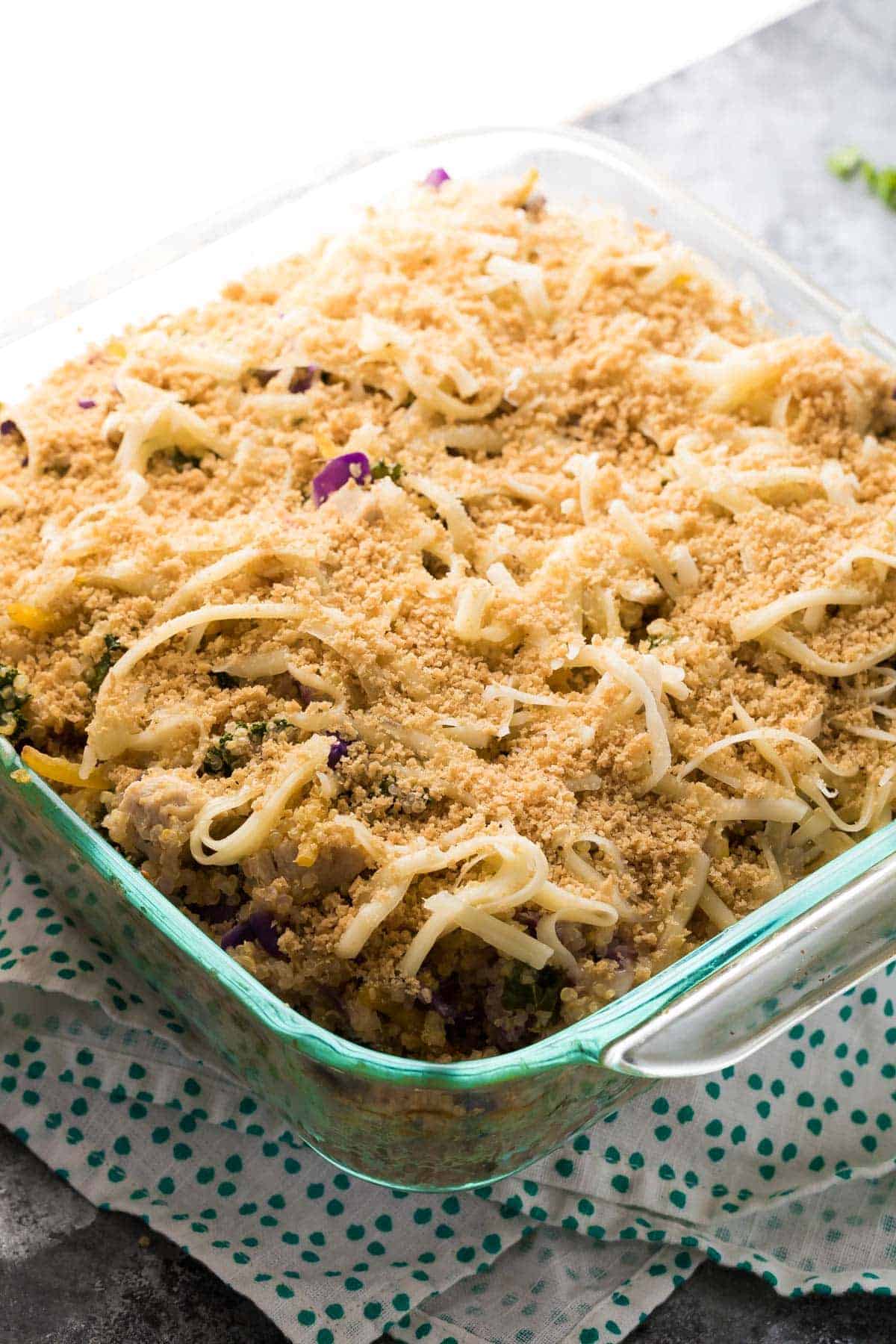 Mediterranean Chicken Quinoa Casserole topped with cheese and panko breadcrumbs in glass baking dish