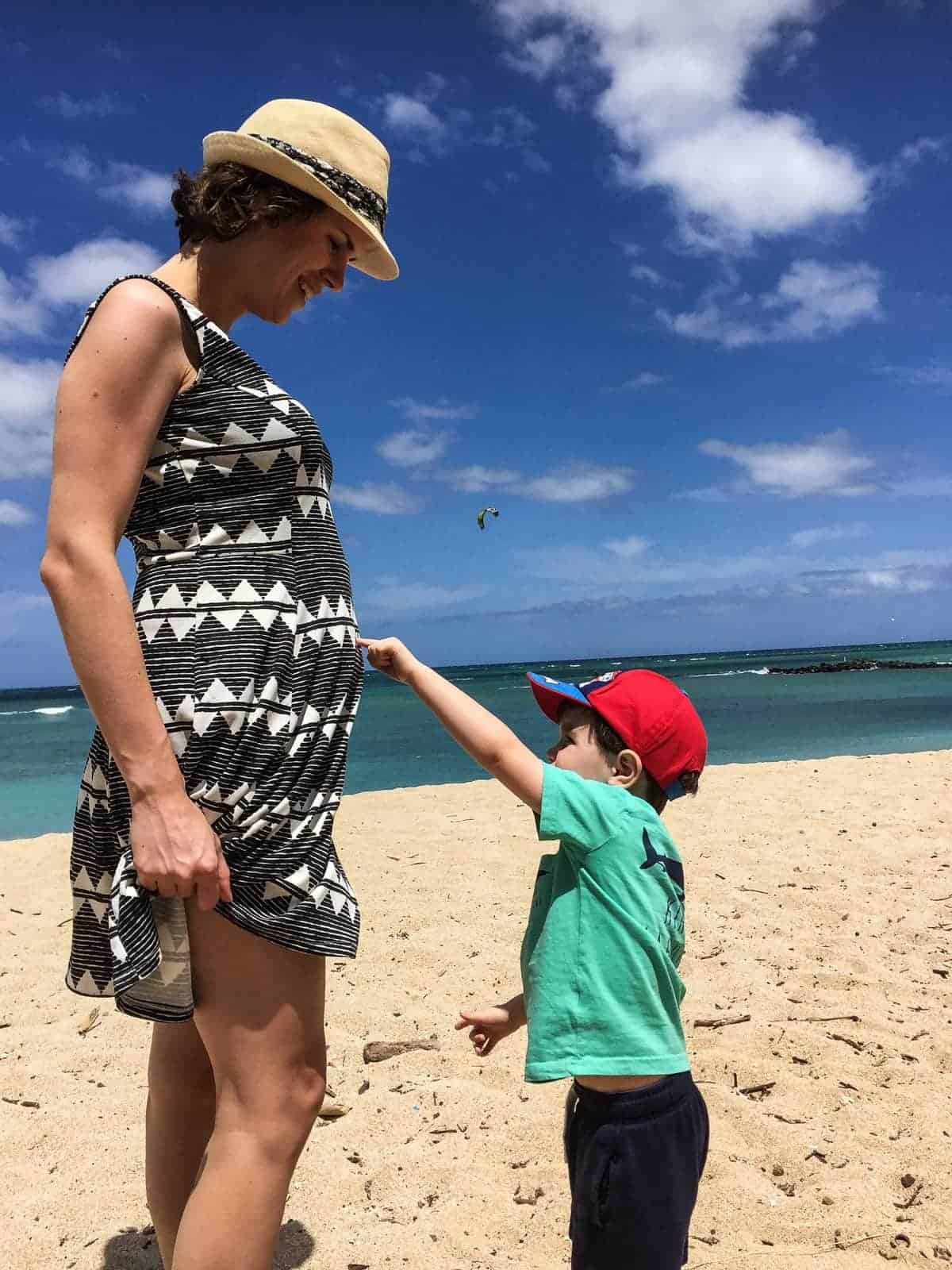 Denise on the beach with a little boy pointing at her stomach