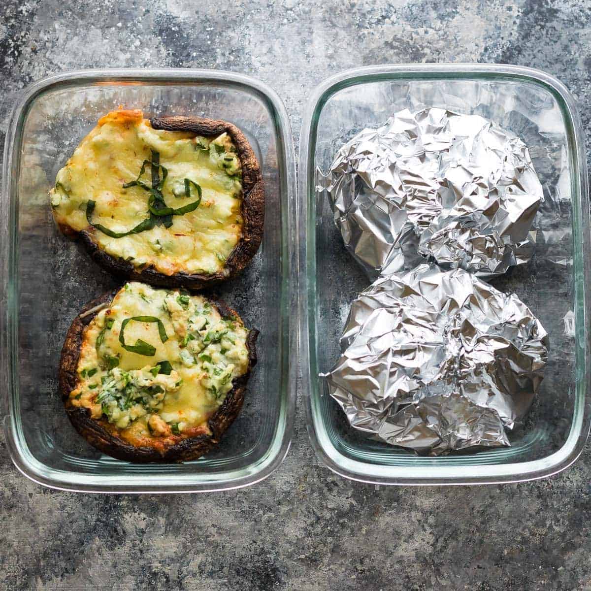 overhead shot of four lasagna stuffed portobello mushrooms with two of them enclosed in tinfoil