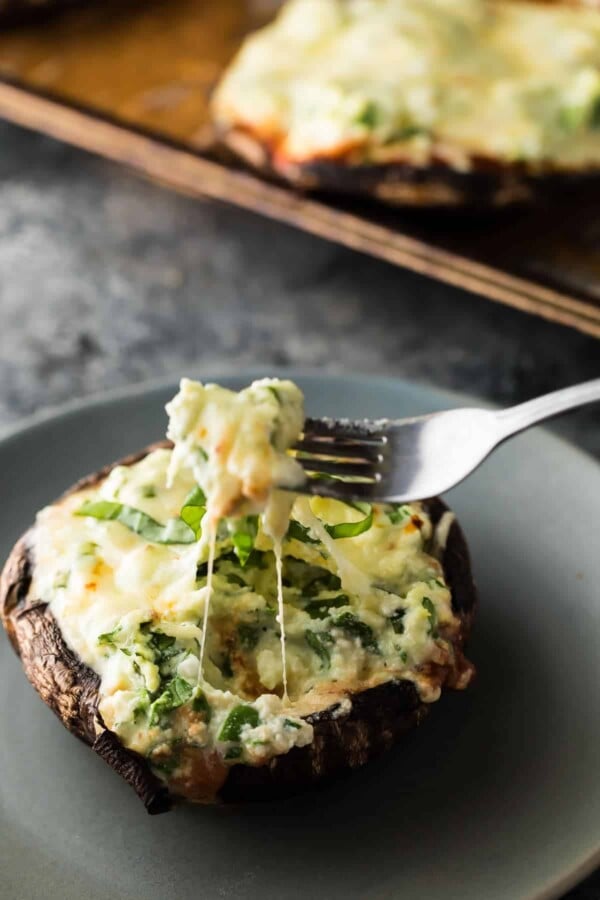 lasagna stuffed portobello mushroom on gray plate with fork taking a bite