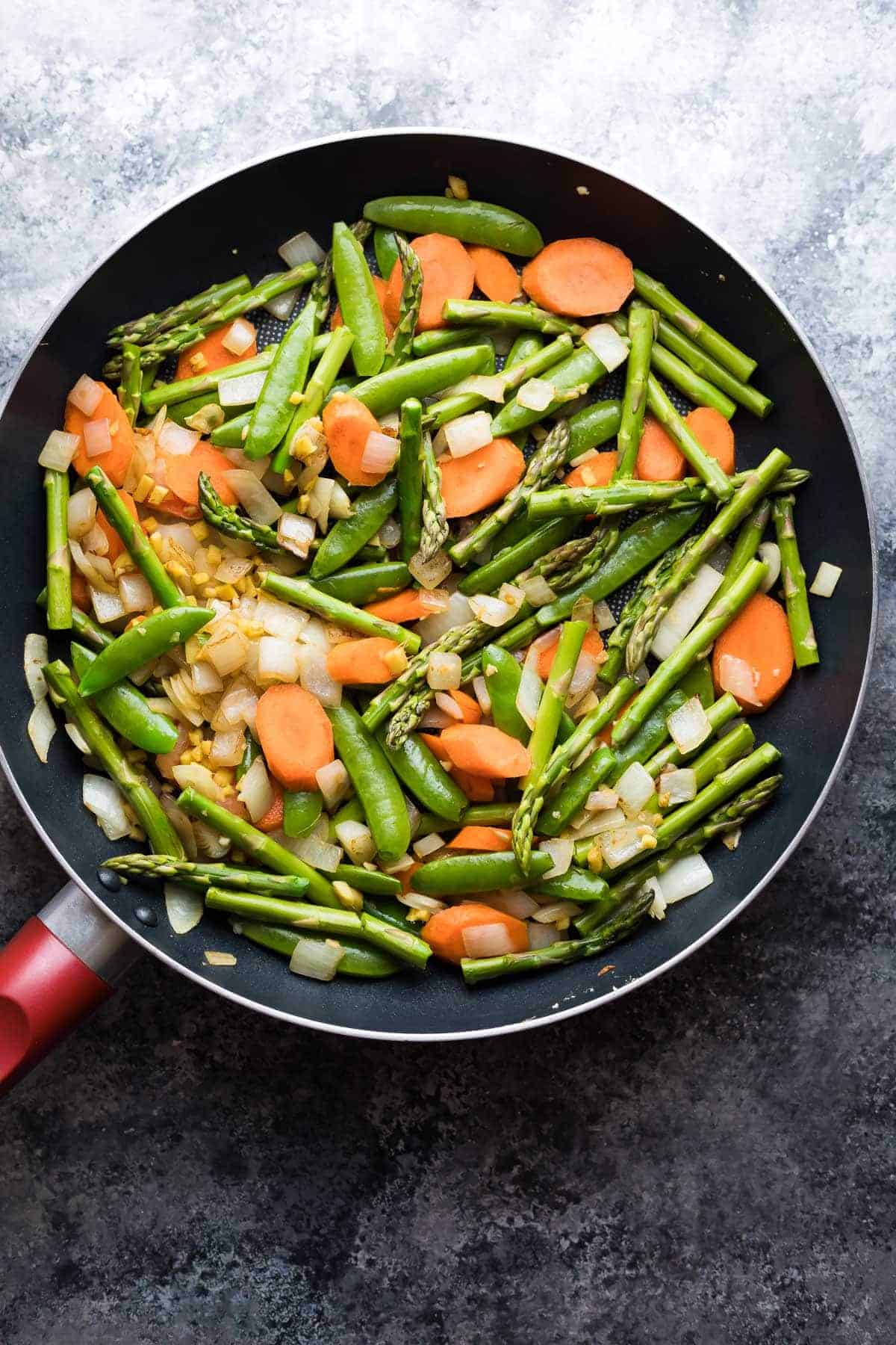 Overhead view of large saute pan filled with variety of chopped veggies