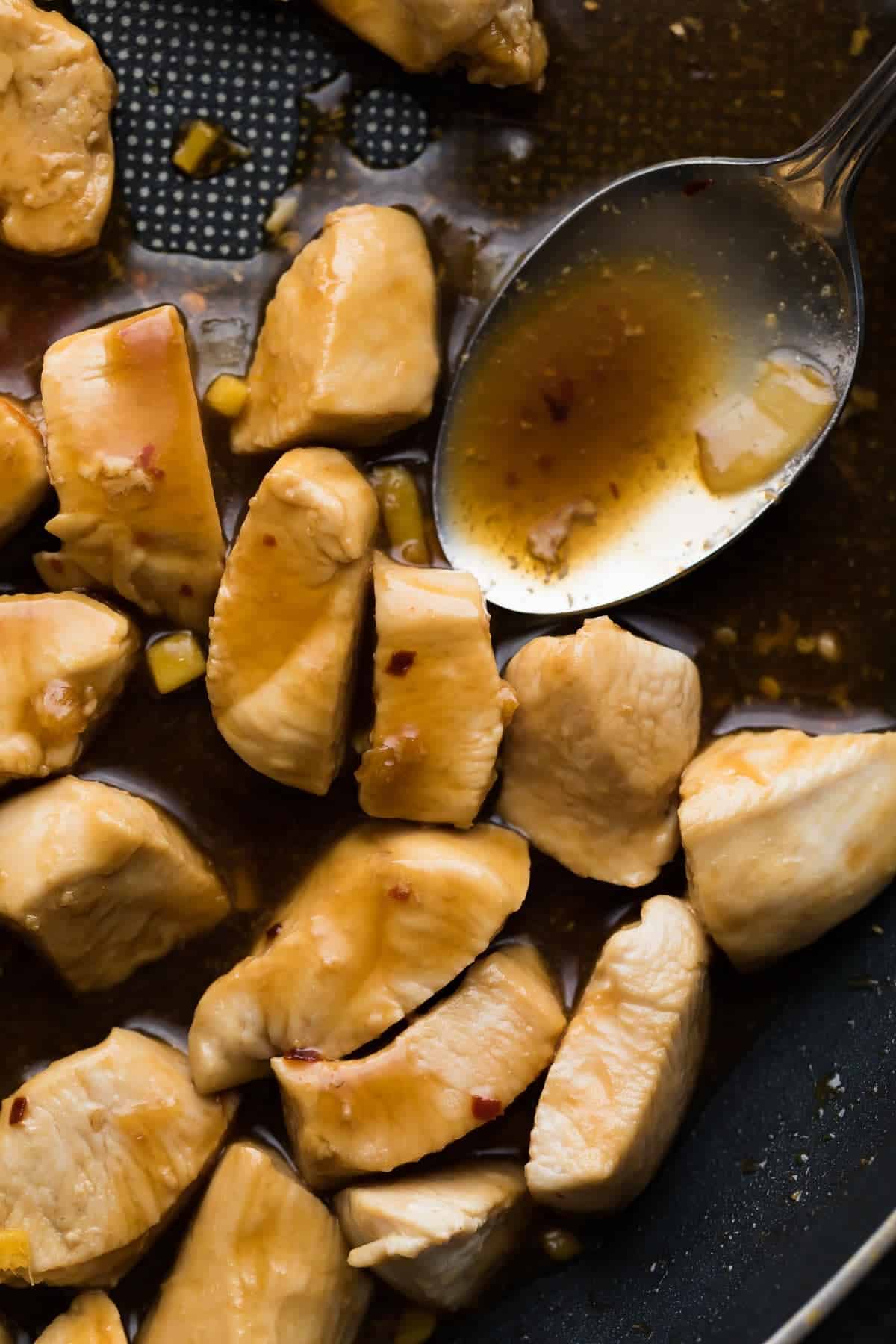 sauce being spooned onto chunks of chicken