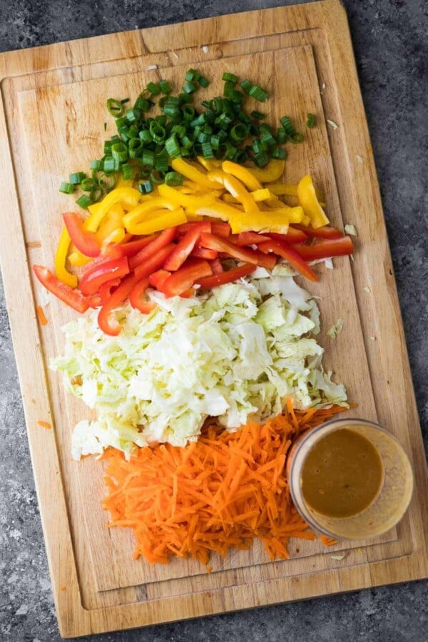 chopped veggies on wood cutting board for satay chicken bowls