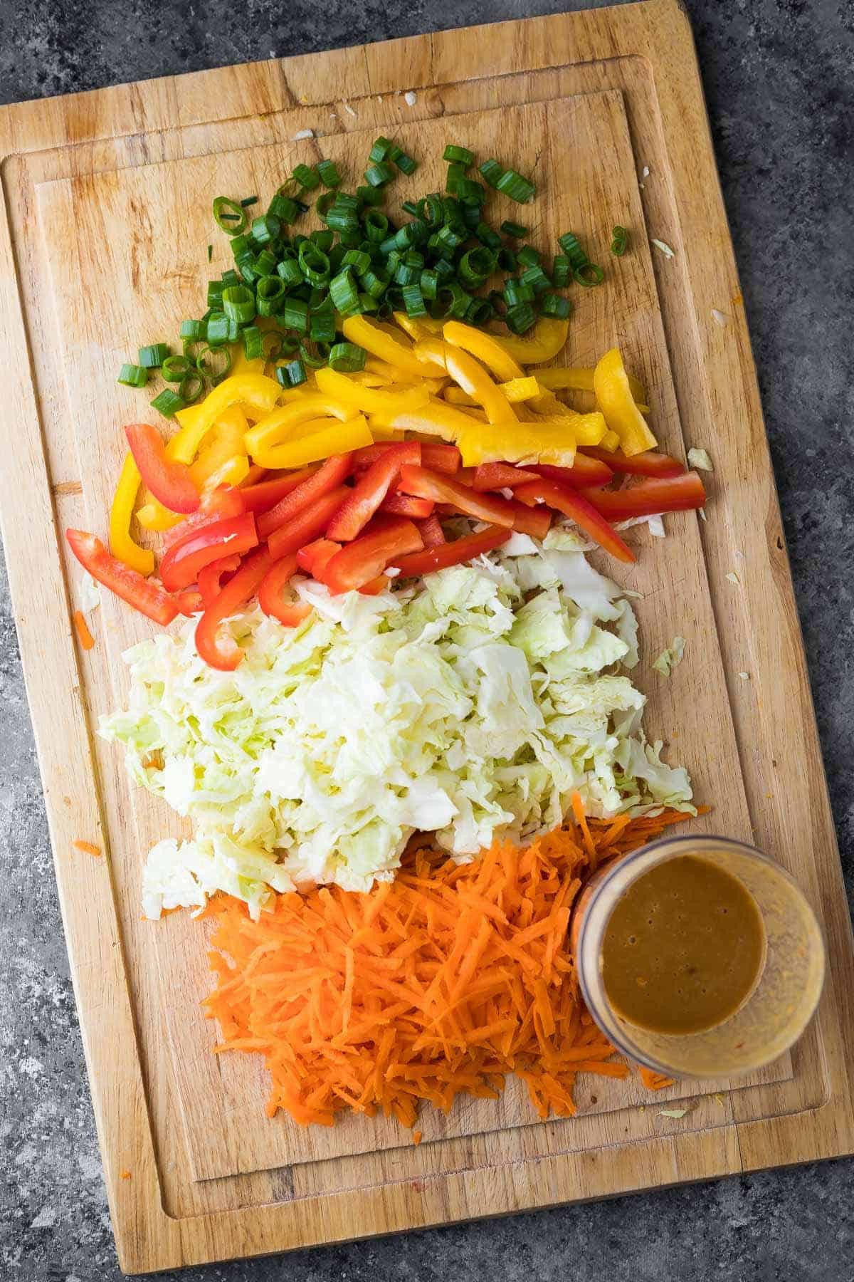 chopped veggies on wood cutting board for satay chicken bowls
