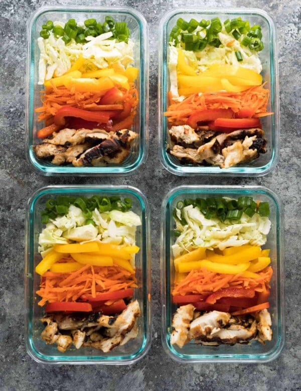 four glass meal prep containers with satay chicken lunch bowls