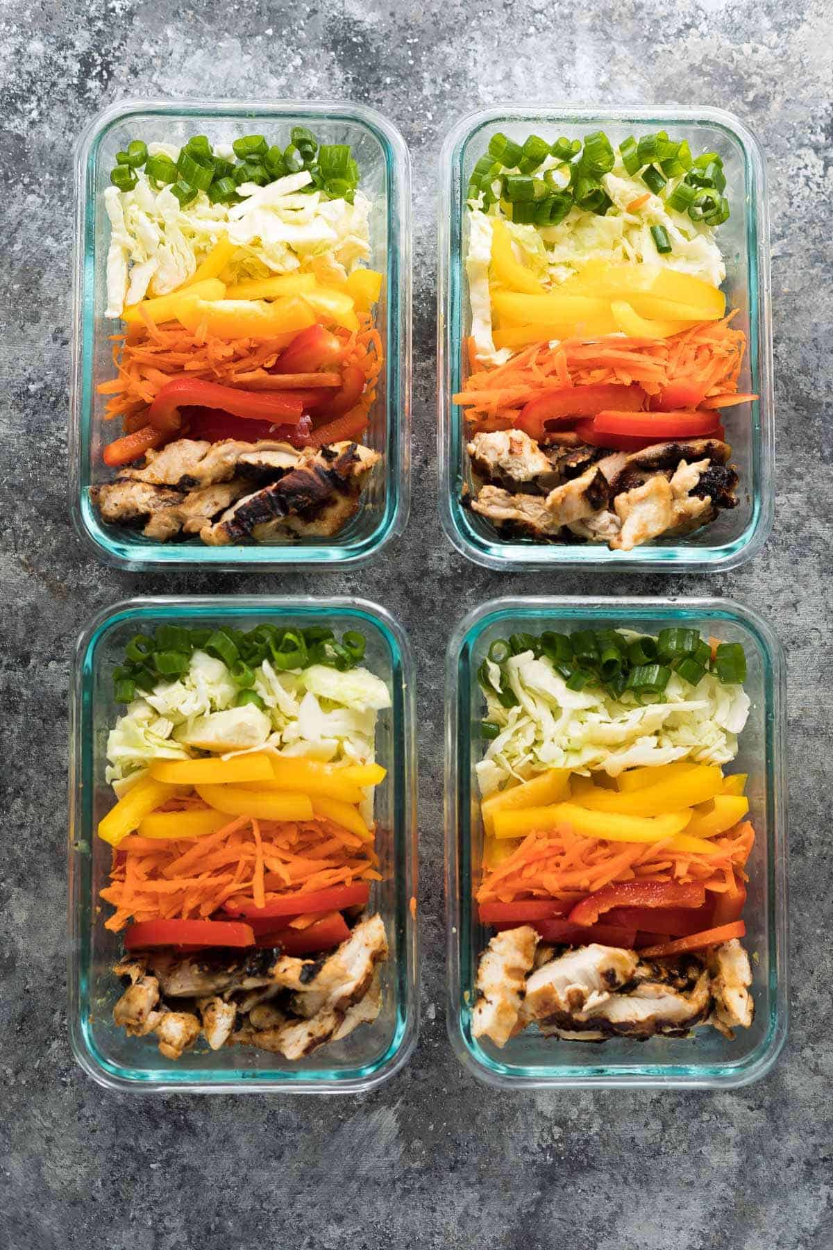 overhead shot of four satay chicken meal prep lunch bowls