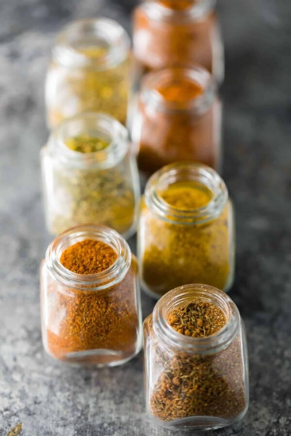 Close up of seven glass jars filled with dry rub recipes