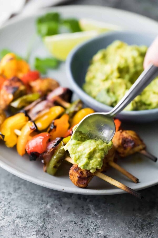 Freezer to grill fajita chicken skewers on gray plate with guacamole