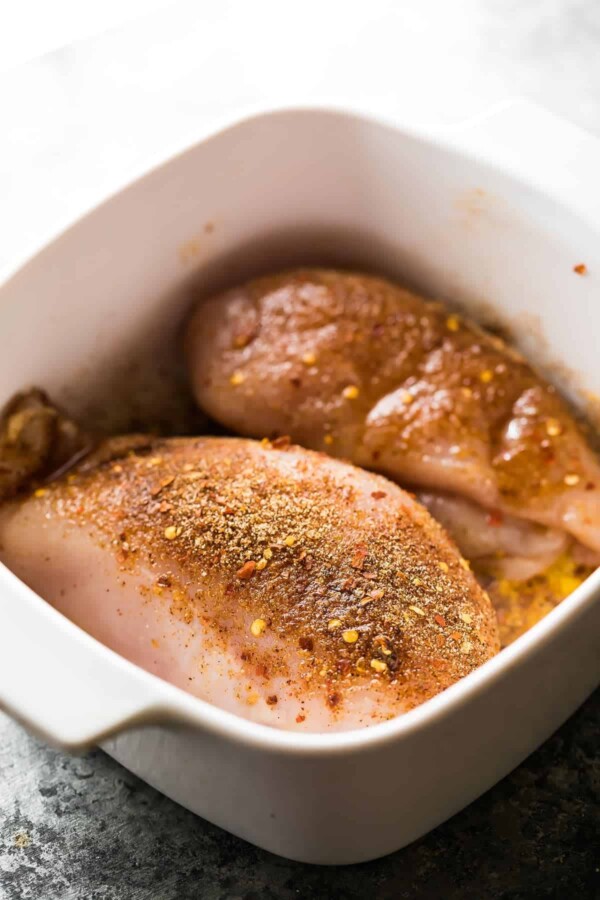 seasoned raw chicken in white baking dish