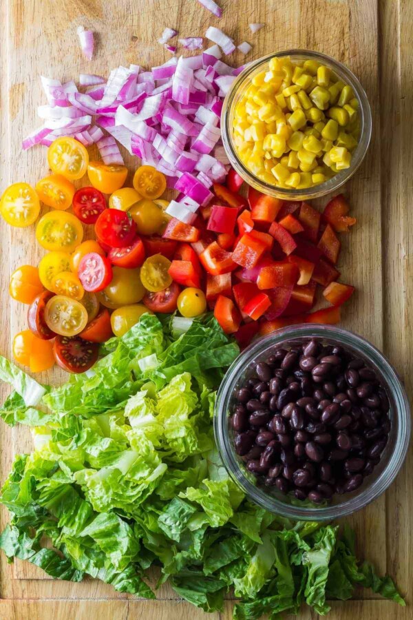 separate ingredients for southwestern chopped chicken salad on wood cutting board