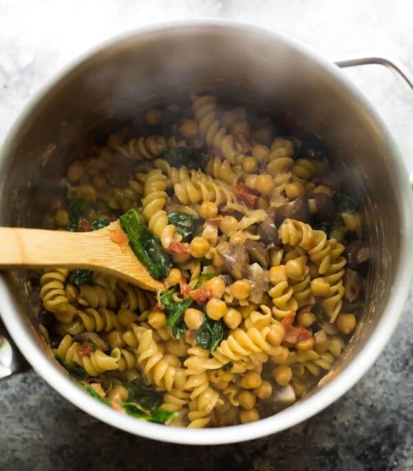 spoon scooping cooked sun dried tomato pasta out of the pot