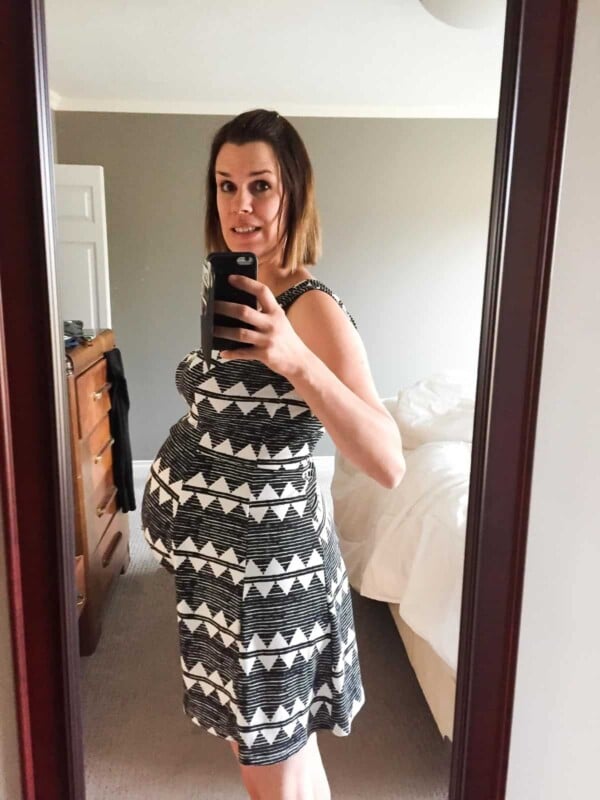 Denise pregnant in front of the mirror in a dress