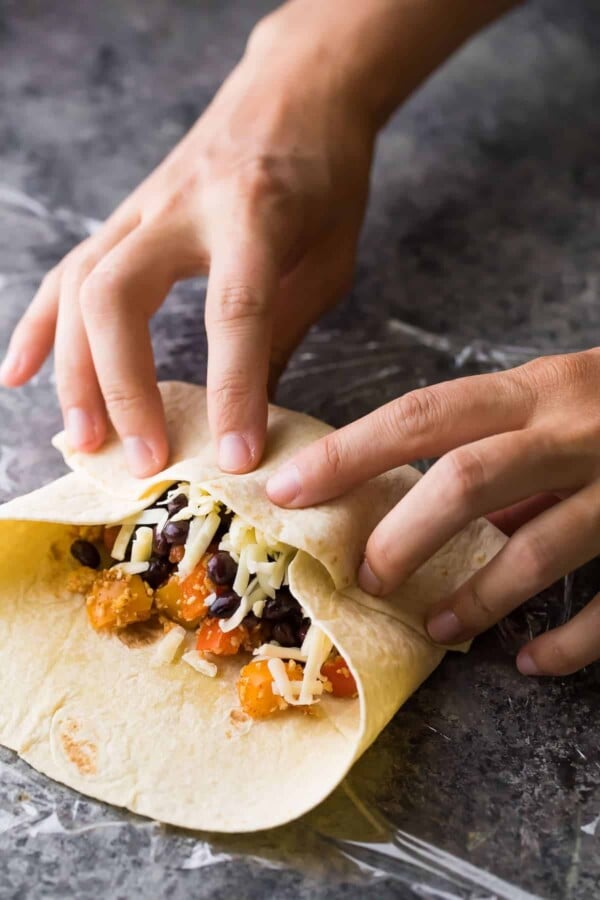 tortilla being rolled up with stuffing inside