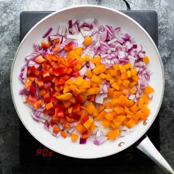 red onion and bell peppers in saute pan