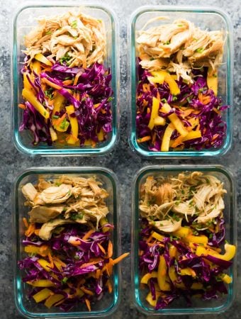 overhead shot of four glass containers filled with chipotle honey chicken taco salad bowls