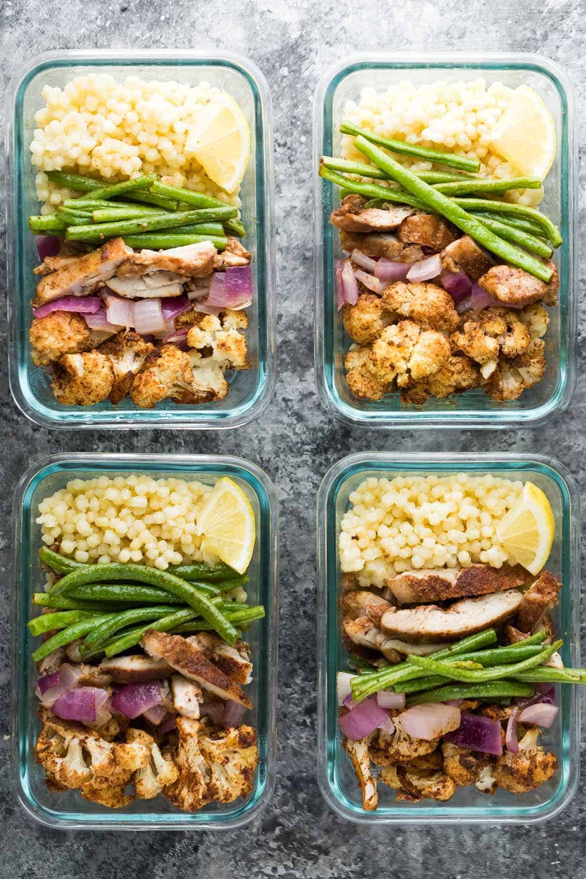 Overhead view of four glass containers with Moroccan couscous meal prep bowls