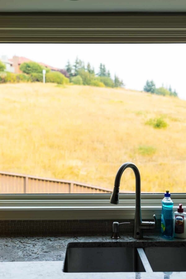 kitchen sink in front of a window with grass in the background