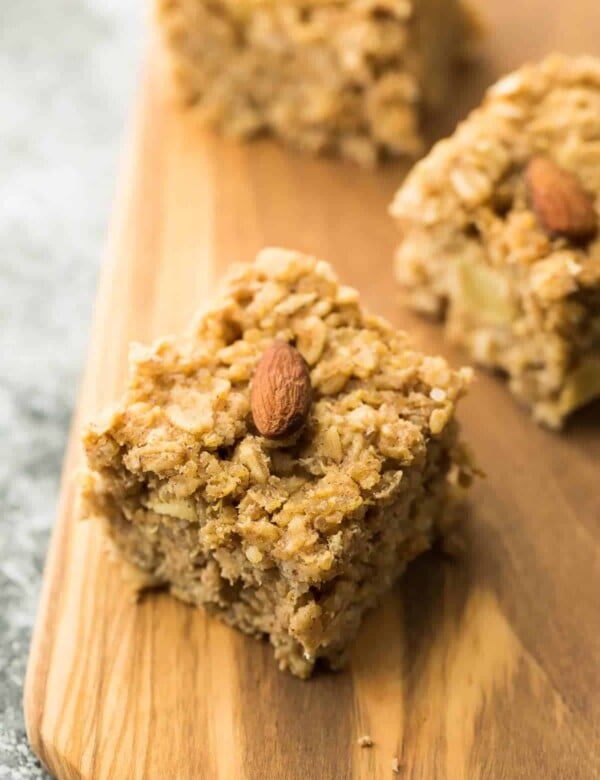 multiple pieces of apple quinoa breakfast bars with almond on top of wood board