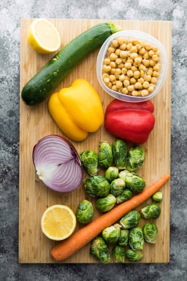 wood cutting board with raw ingredients for Chickpea Buddha Bowls and Greek Chicken Wraps