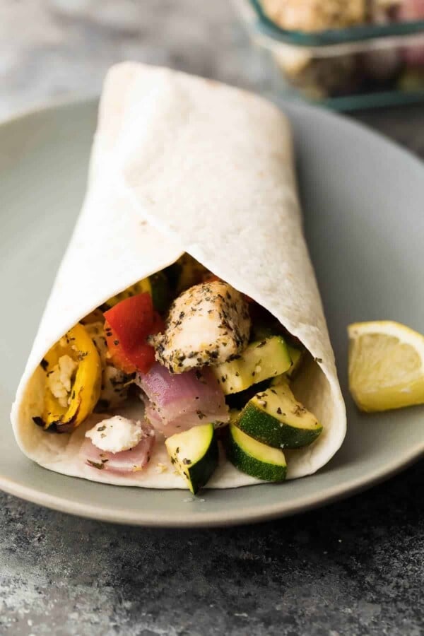 Greek chicken wraps in a tortilla on gray plate