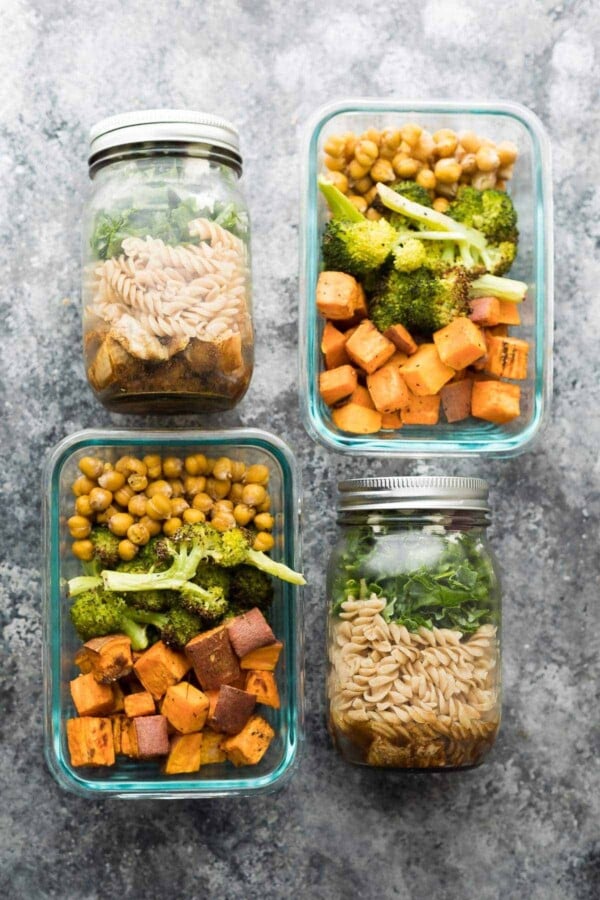 Overhead view of four pasta jar salads and sweet potato, chickpea, broccoli bowls