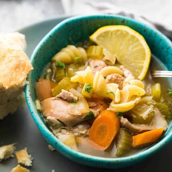 blue bowl with lemon ginger chicken noodle soup with lemon and bread