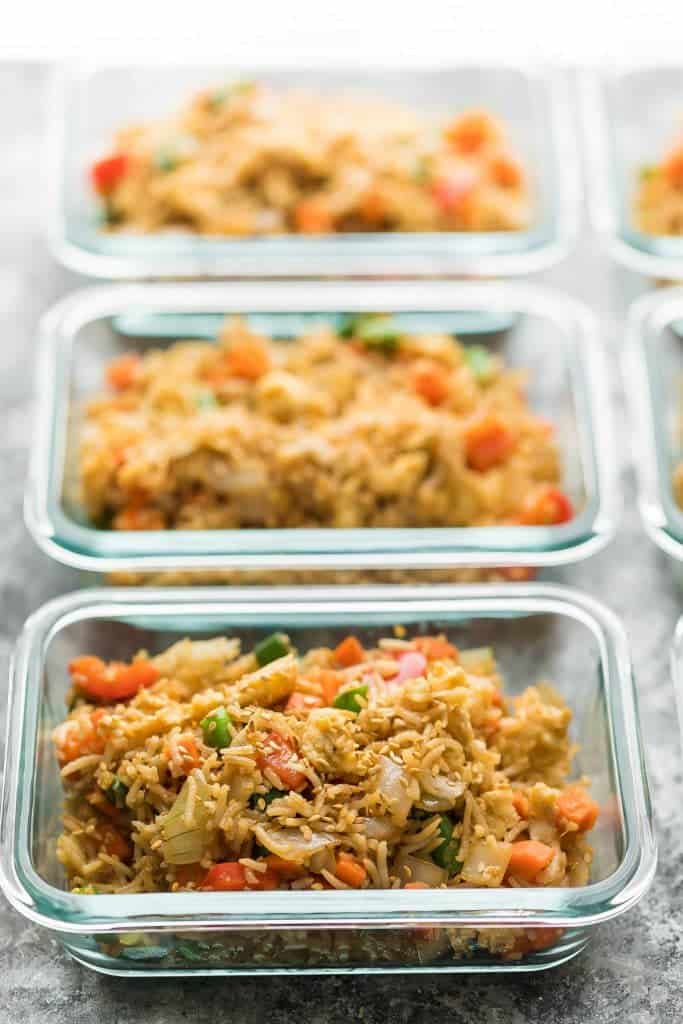 row of glass meal prep containers filled with egg fried rice