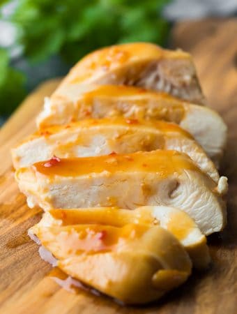 A close up of sliced sweet chili chicken on wood cutting board