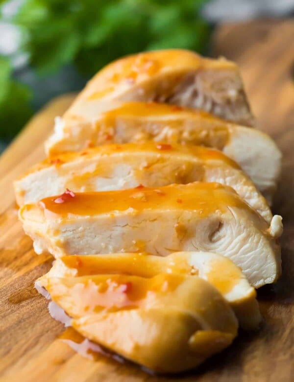 A close up of sliced sweet chili chicken on wood cutting board