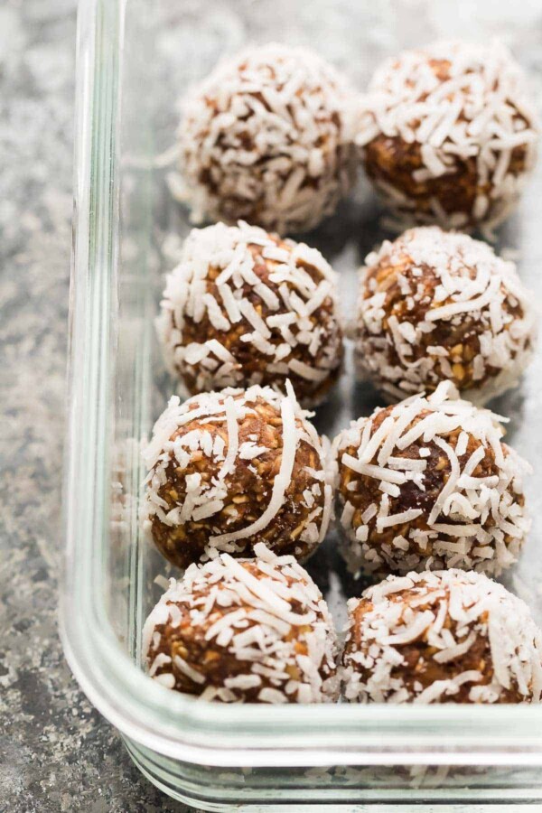 eight nut free energy bites rolled in shredded coconut in glass container