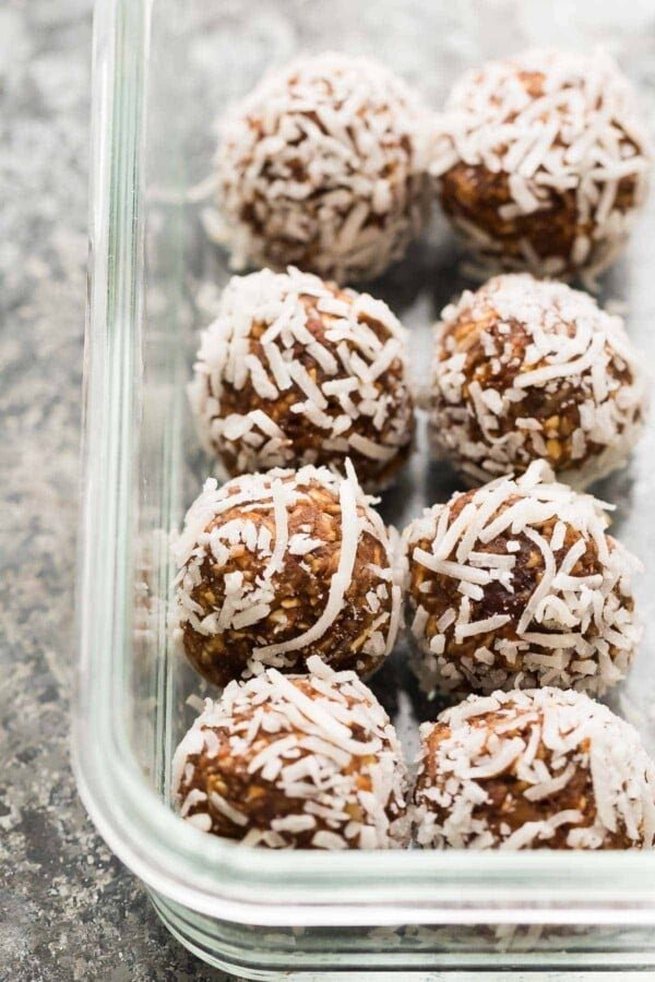 eight nut free energy bites rolled in shredded coconut in glass container