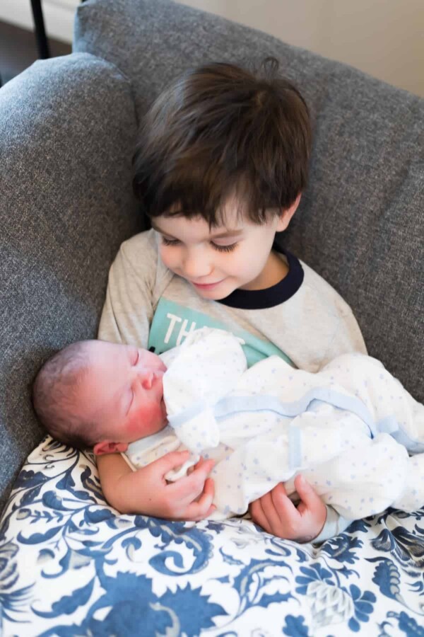 a small boy holding a newborn baby