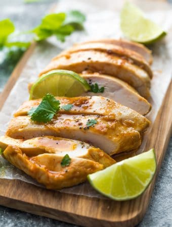 sliced chicken on wood cutting board with fresh limes and chipotle chicken marinade