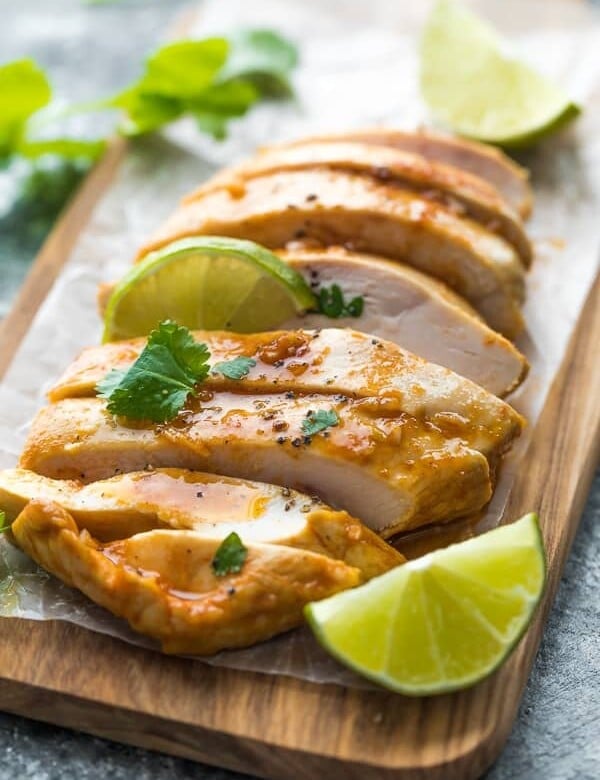 sliced chicken on wood cutting board with fresh limes and chipotle chicken marinade